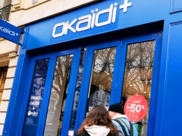 Devanture d’un magasin Okaïdi avec des clients et des affiches de liquidation en France.