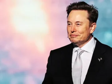 Elon Musk devant une fusée SpaceX et les écrans de Wall Street