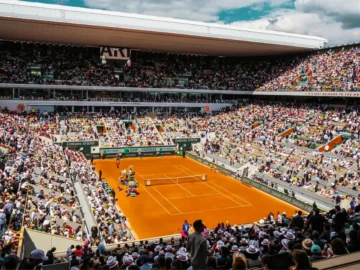 Joueur de tennis en pleine action sur un court de Roland-Garros lors d'un match à fort enjeu.