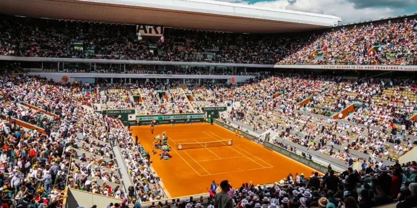 Joueur de tennis en pleine action sur un court de Roland-Garros lors d'un match à fort enjeu.